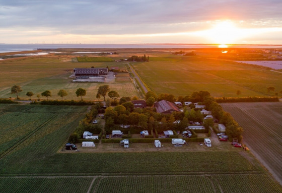 Solnedgang over Camping 'de Val' i Zeeland, Holland med marker, campingvogne og det fredelige landskab.