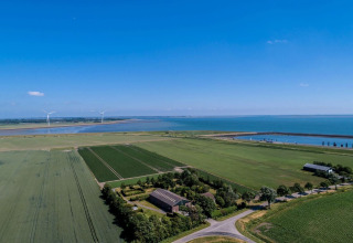 Vue aérienne du Camping 'de Val' en Zélande, Pays-Bas, champs, mer, éoliennes et ciel dégagé.