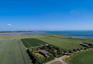 Vue aérienne du Camping 'de Val' en Zélande, Pays-Bas, champs, mer, éoliennes et ciel dégagé.
