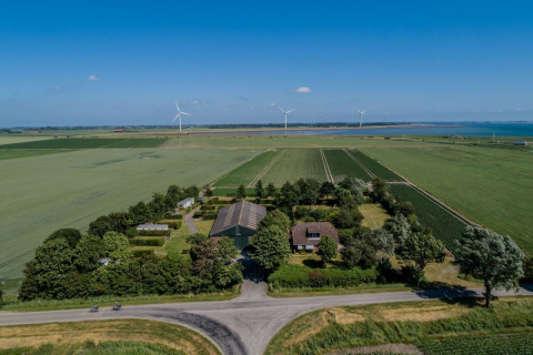 Vue aérienne de Camping 'de Val' à Zeeland, Pays-Bas, entouré de champs, d’éoliennes et vue sur la mer.