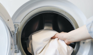 A hand places white laundry into a front-loading washing machine at a holiday park glamping accommodation.