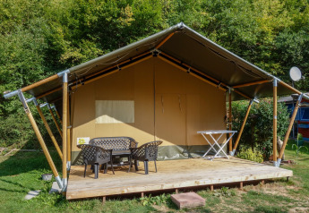 Tienda safari con terraza y muebles en Camping Bockenauer Schweiz en Alemania, rodeada de vegetación.