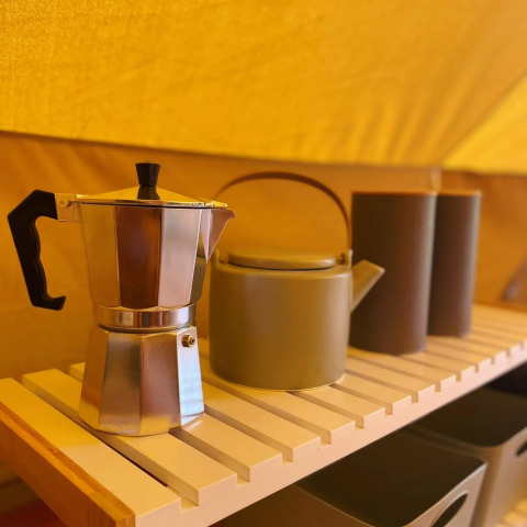 Caffettiera e teiera su una mensola di legno in una tenda safari Belltent a Camping Drei Spatzen, Germania.