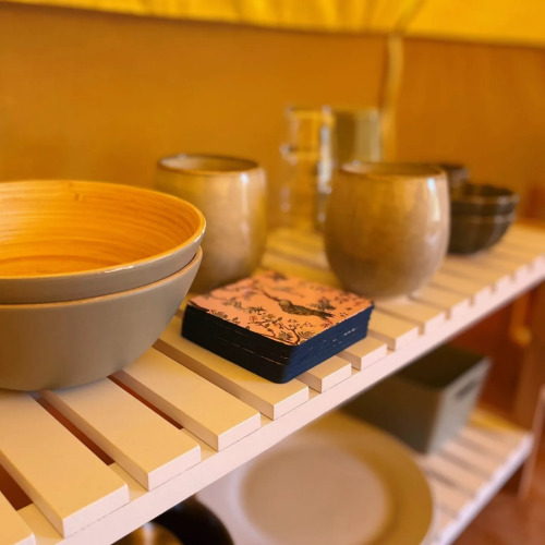 Schüsseln, Becher und Servietten auf einem Regal im gemütlichen Belltent-Safarizelt bei Camping Drei Spatzen.