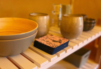 Cuencos, tazas y servilletas sobre una repisa en la carpa tipo safari Belltent en Camping Drei Spatzen, Alemania.