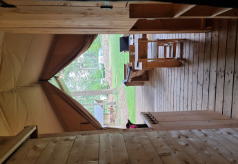 Vista desde una tienda safari con terraza de madera y bancos en Camping Bockenauer Schweiz, Alemania.