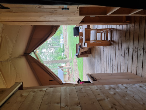 Vue d’une tente safari avec terrasse en bois et bancs au Camping Bockenauer Schweiz en Allemagne.