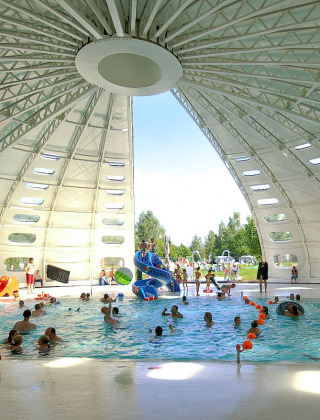 Piscina cubierta con techo abovedado y personas disfrutando en hu Birkelt Village, en Mersch, Luxemburgo.