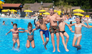 Niños saltando a la piscina en el parque vacacional hu Birkelt Village en Mersch, Luxemburgo, día soleado.