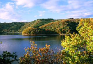 Zicht op meer, bosrijke heuvels en kleurrijke bomen bij hu Birkelt Village in Mersch, Luxemburg.