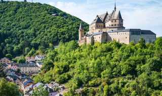 Vista de un castillo histórico rodeado de vegetación y casas coloridas en Larochette, Mersch, Luxemburgo.