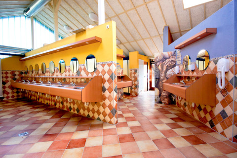 Colorful and spacious washroom featuring multiple sinks and round mirrors at hu Birkelt Village in Mersch, Luxembourg.
