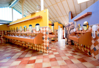 Colorful and spacious washroom featuring multiple sinks and round mirrors at hu Birkelt Village in Mersch, Luxembourg.