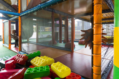 Parco giochi al coperto con un bambino piccolo, grandi blocchi colorati e struttura da arrampicata in Lussemburgo.