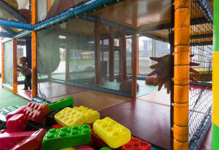 Indoor speeltuin met kleurrijke bouwstenen en een klein kind bij een klimstructuur in Luxemburg vakantiepark.