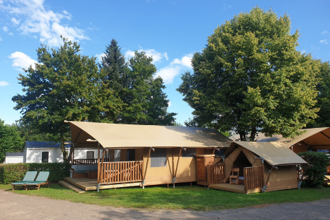 Tiendas safari SunLodge Taiga & Kambi en hu Birkelt Village, Luxemburgo, rodeadas de árboles verdes.