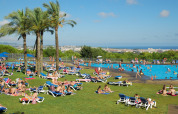 Gæster slapper af ved poolen i Camping Vilanova Park, omgivet af palmer og udsigt over Catalonien, Spanien.