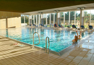 Piscina coperta con lettini e grandi finestre al Camping Vilanova Park, un villaggio turistico in Catalogna, Spagna.