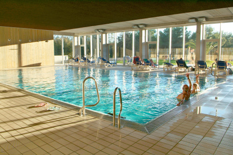 Piscina coperta con lettini e grandi finestre al Camping Vilanova Park, un villaggio turistico in Catalogna, Spagna.