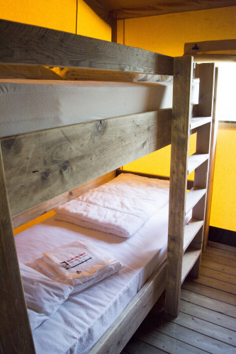 Una litera de madera en una tienda safari en Glamping de Vakantiepark Klein Strand, Bélgica.
