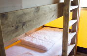 Un letto a castello di legno in una tenda safari nel Glamping di Vakantiepark Klein Strand, Belgio.