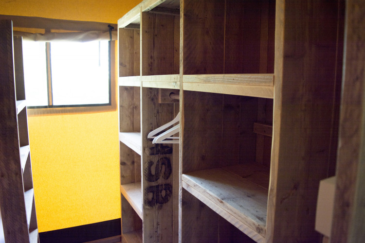 Estantes de madera y perchas en una tienda safari de Glamping en Vakantiepark Klein Strand, Bélgica.