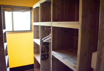 Estantes de madera y perchas en una tienda safari de Glamping en Vakantiepark Klein Strand, Bélgica.