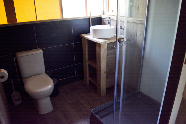 Baño en la tienda safari Glamping en Vakantiepark Klein Strand con inodoro, ducha y lavabo.