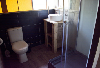Baño en la tienda safari Glamping en Vakantiepark Klein Strand con inodoro, ducha y lavabo.