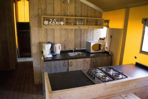 Keuken in een safaritent Glamping op Vakantiepark Klein Strand in België, met fornuis en magnetron.