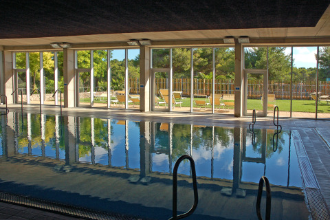 Indoor swimming pool with large glass windows and garden views at Camping Vilanova Park, Catalonia, Spain.