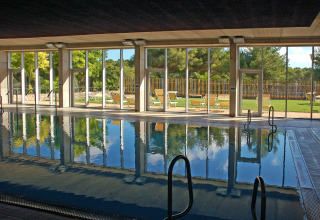 Piscina coperta con grandi finestre e vista sul giardino presso Camping Vilanova Park, Catalogna, Spagna.