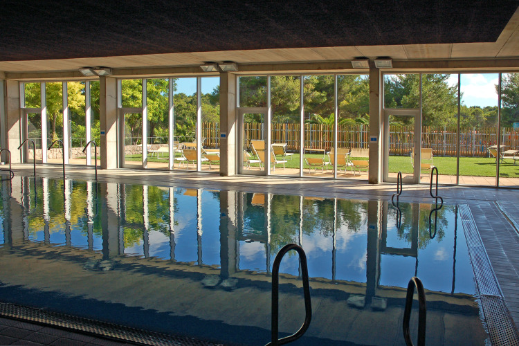 Piscine intérieure avec de grandes baies vitrées et vue sur jardin à Camping Vilanova Park, Catalogne, Espagne.