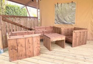Holzmöbel auf einer Terrasse in einem Safarizelt bei Glamping im Vakantiepark Klein Strand, Belgien.