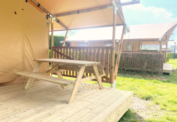Tavolo da picnic in legno su veranda di tenda safari al Glamping, Vakantiepark Klein Strand, Belgio.