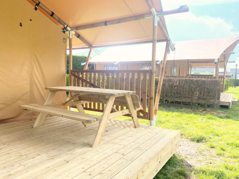 Tavolo da picnic in legno su veranda di tenda safari al Glamping, Vakantiepark Klein Strand, Belgio.