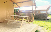 Mesa de picnic de madera en la terraza de una tienda safari en Glamping, Vakantiepark Klein Strand, Bélgica.