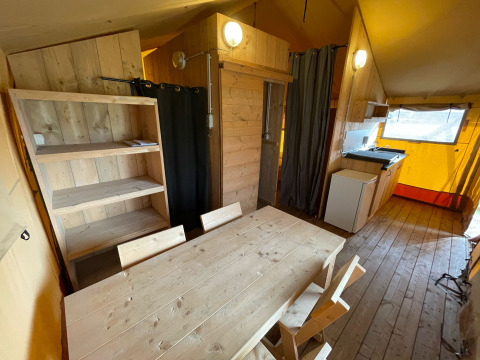 Interior de una tienda safari en Glamping Vakantiepark Klein Strand en Bélgica, con muebles de madera.