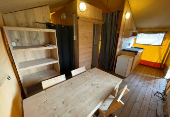 Interior de una tienda safari en Glamping Vakantiepark Klein Strand en Bélgica, con muebles de madera.