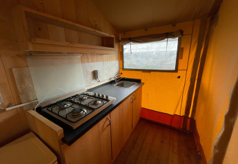 Área de cocina en una tienda safari de Glamping en Vakantiepark Klein Strand, Bélgica, con estufa y fregadero.
