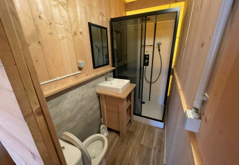 Bagno moderno con pareti in legno, doccia, WC e lavabo in una tenda safari glamping in Belgio.