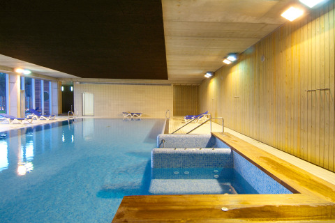 Indoor swimming pool and relaxation area with loungers at Camping Vilanova Park in Catalonia, Spain.