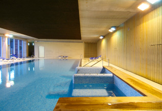 Indoor swimming pool and relaxation area with loungers at Camping Vilanova Park in Catalonia, Spain.