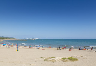 Bagnanti e famiglie sulla spiaggia sabbiosa vicino a Camping Vilanova Park in Catalogna, Spagna.