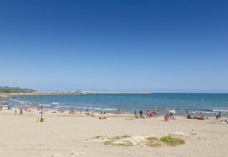 Families relaxing and swimming on the sandy beach near Camping Vilanova Park in Catalonia, Spain.