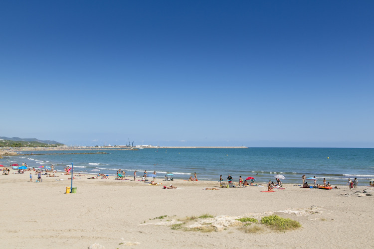 Plage animée avec vacanciers près du Camping Vilanova Park sous le soleil de Catalogne, Espagne.