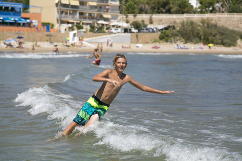 Ragazzo gioca in mare vicino alla spiaggia a Camping Vilanova Park, villaggio turistico in Catalogna, Spagna, estate.