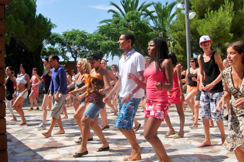 A group of people participates in an outdoor dance class at Camping Vilanova Park in Catalonia, Spain.