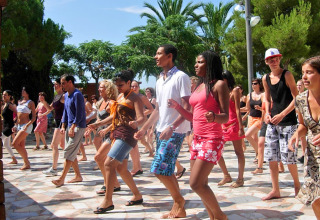 A group of people participates in an outdoor dance class at Camping Vilanova Park in Catalonia, Spain.