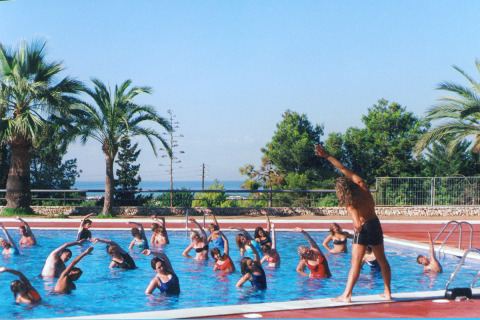 Aquagym class in the pool at Camping Vilanova Park, a holiday park with palm trees in Catalonia, Spain.